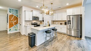 Una cocina moderna con armarios blancos, electrodomésticos de acero inoxidable y una isla central con taburetes.