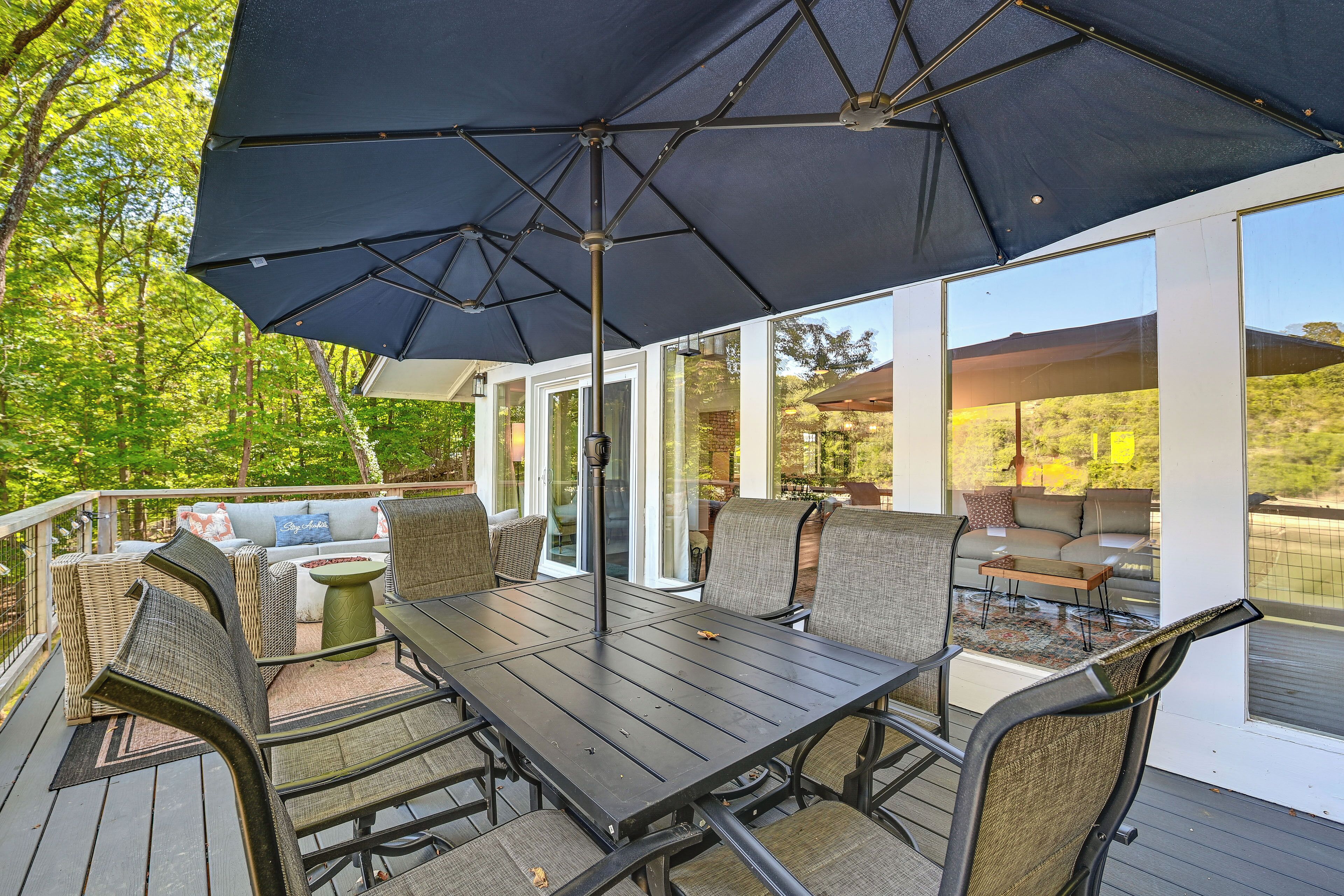 An outdoor deck with a dining table, chairs, and a large umbrella.