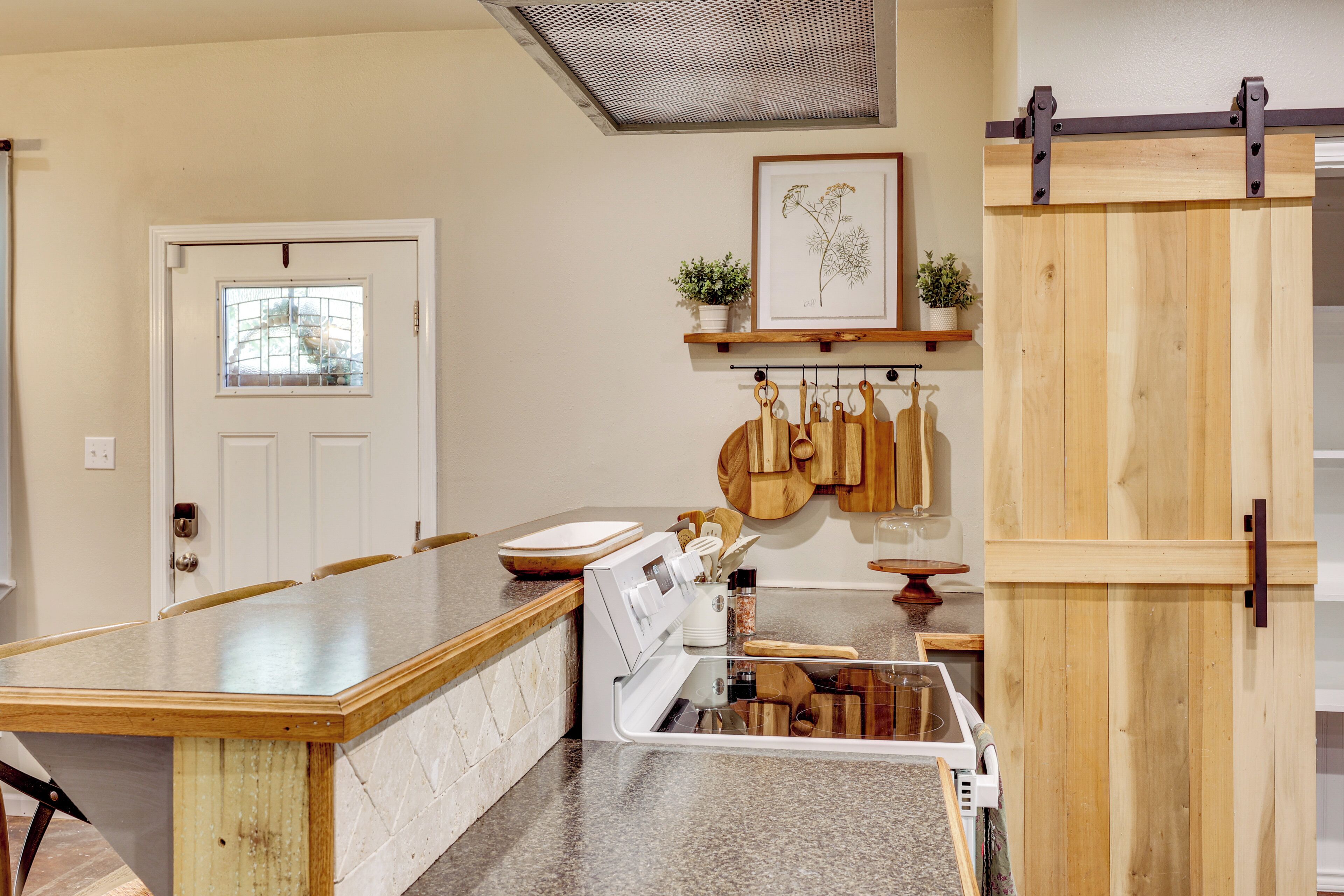 A kitchen with a wooden island, white appliances, and a hanging pot rack.