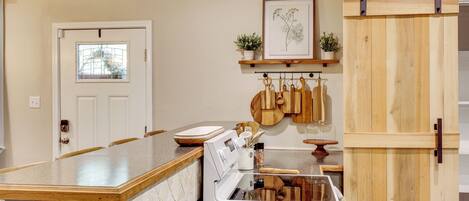 A kitchen with a wooden island, white appliances, and a hanging pot rack.