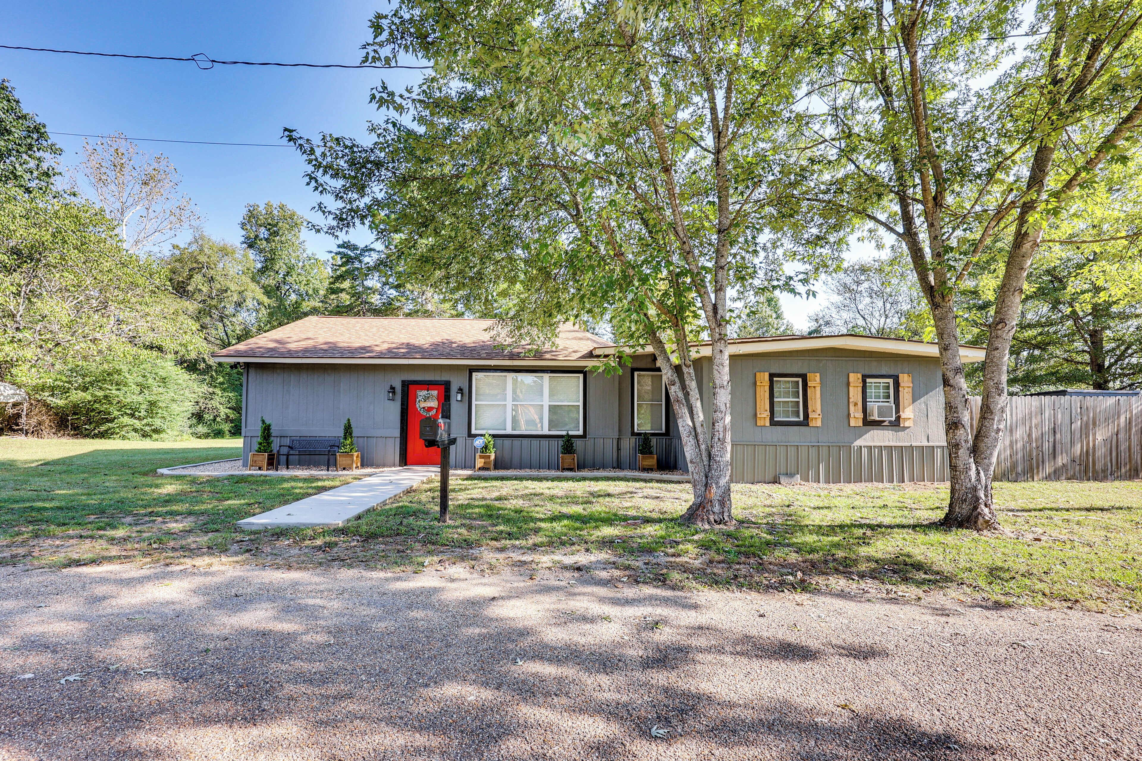 A two-story house with a red door, a front porch, and a small front yard.