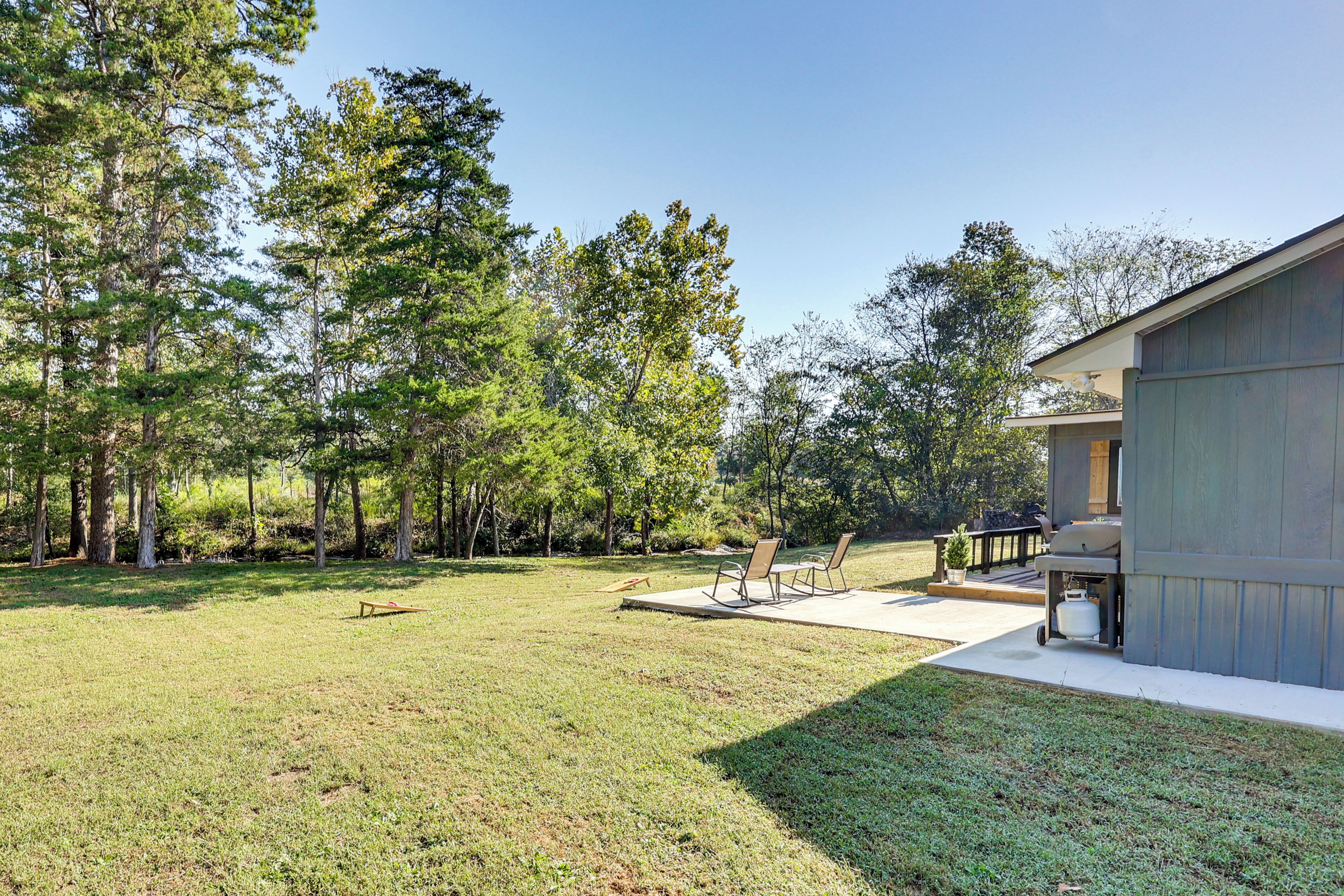A backyard with a patio, two chairs, and a grill area.