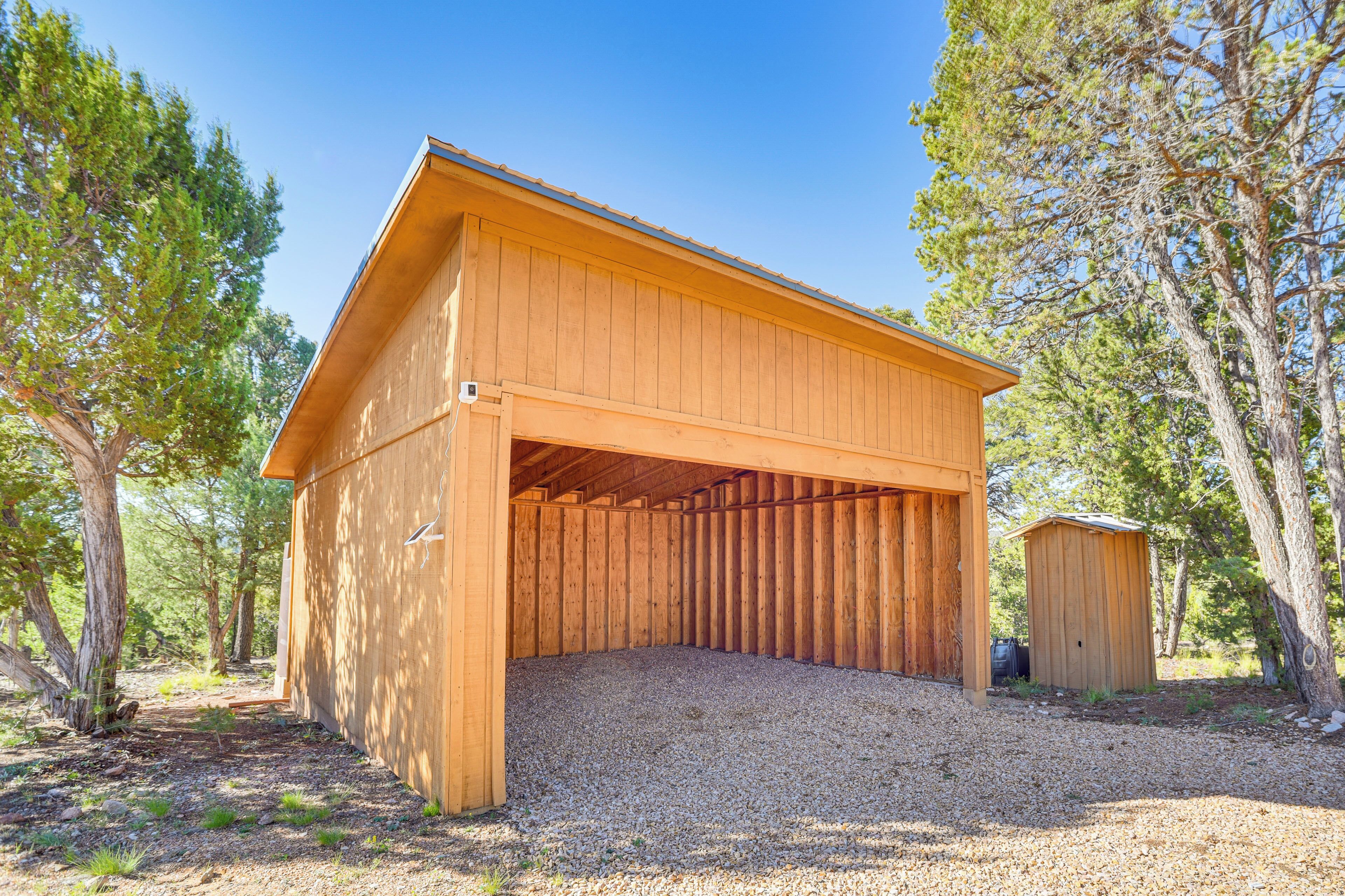 A wooden building with a sloped roof and an open front, surrounded by trees.