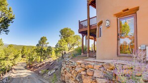 A rustic building with a stone wall, wooden balcony, and a door with a framed picture. - Panoramic Vistas: Glorieta Adobe Near Pecos River (Glorieta)