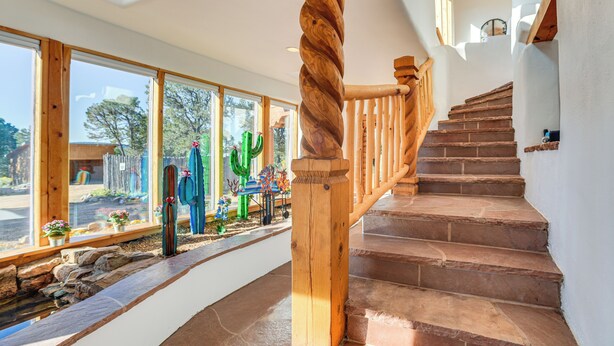 A wooden staircase with a spiral handrail leading to a landing. - Panoramic Vistas: Glorieta Adobe Near Pecos River (Glorieta)