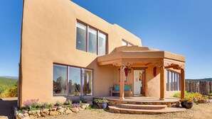 A modern house with a large porch, large windows, and a stone foundation. - Panoramic Vistas: Glorieta Adobe Near Pecos River (Glorieta)