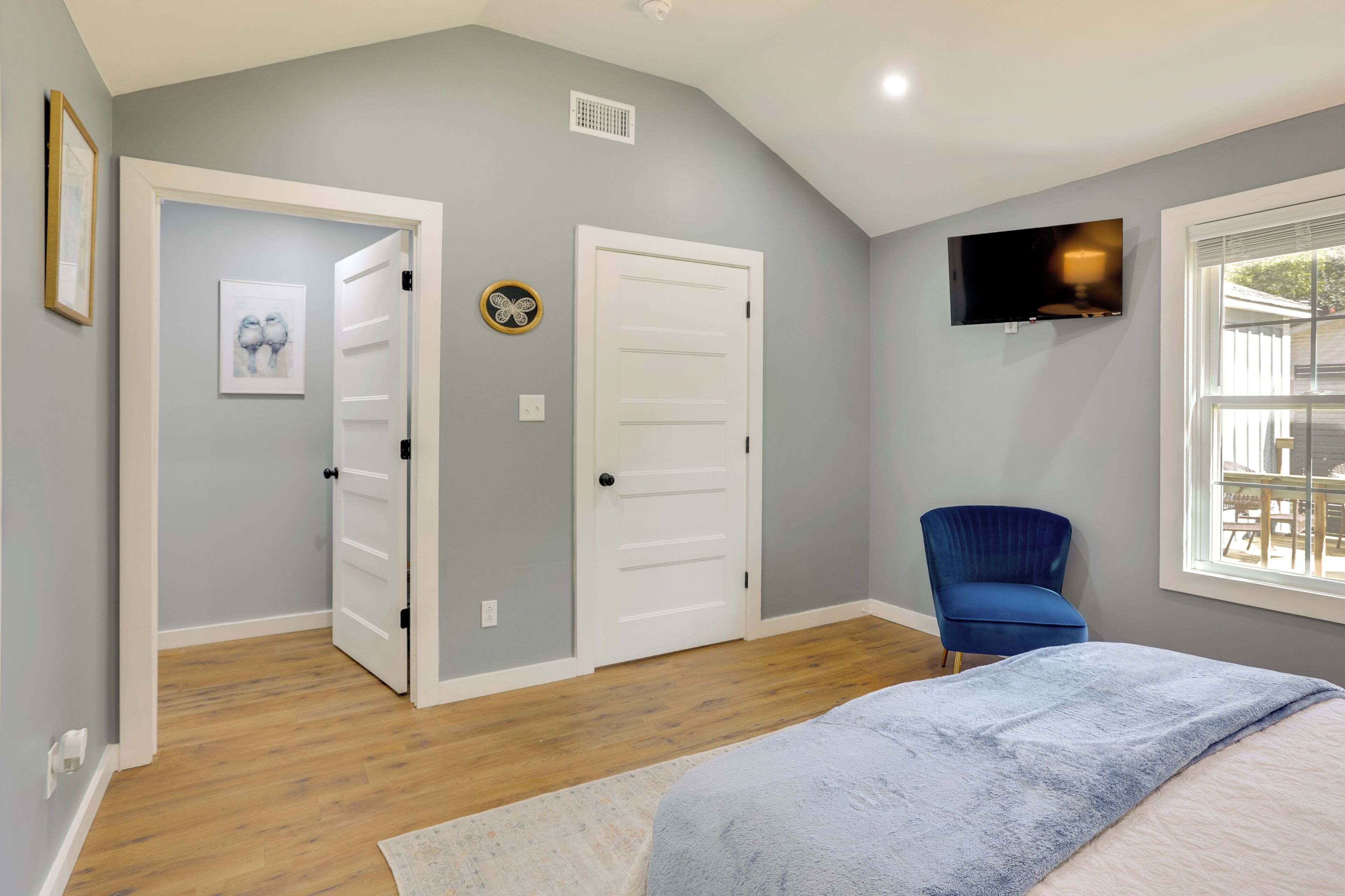 A bedroom with a bed, a TV, a chair, and a door.