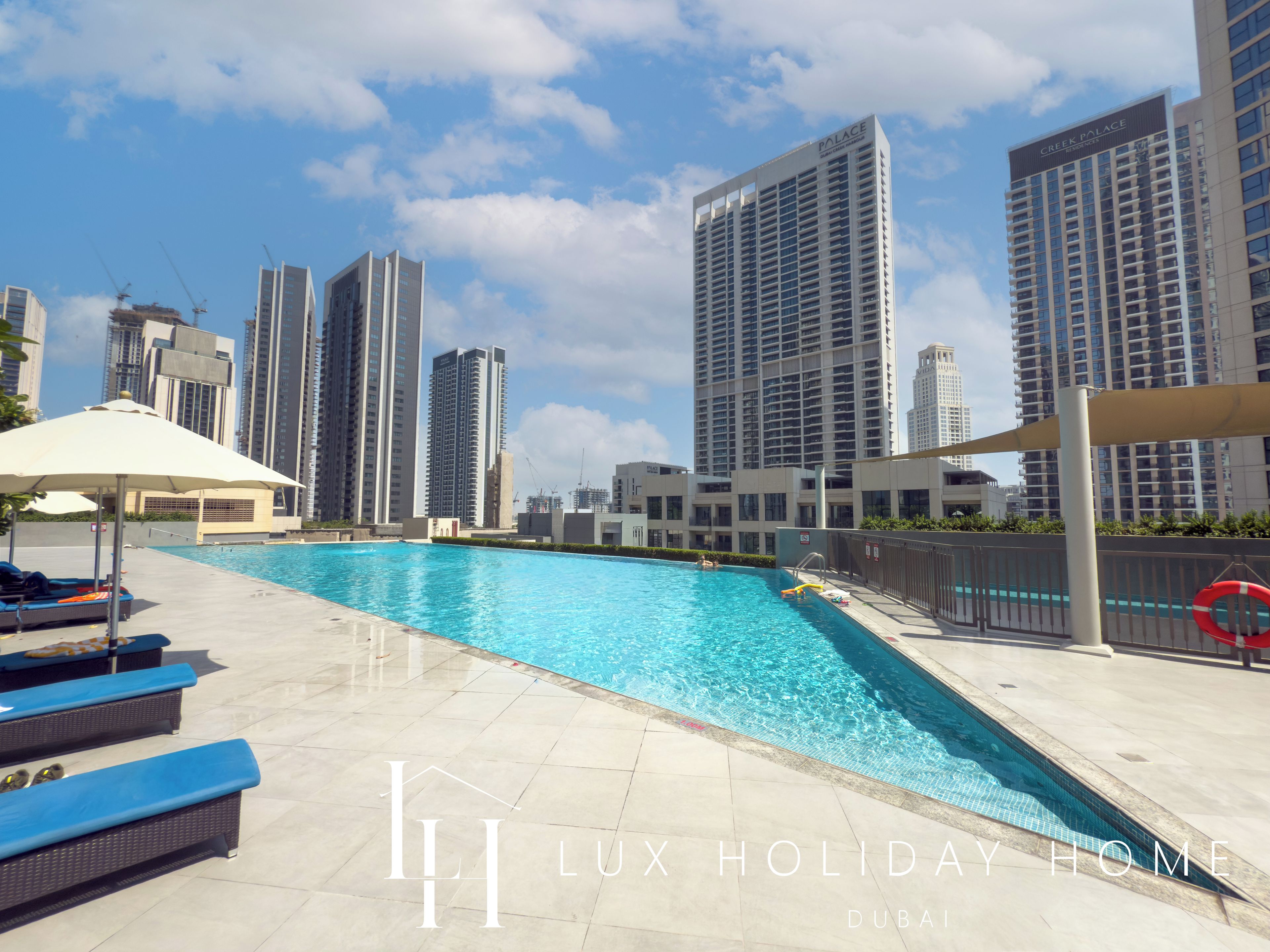 A swimming pool area with lounge chairs and a view of high-rise buildings.