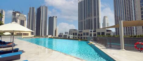 A swimming pool area with lounge chairs and a view of high-rise buildings.
