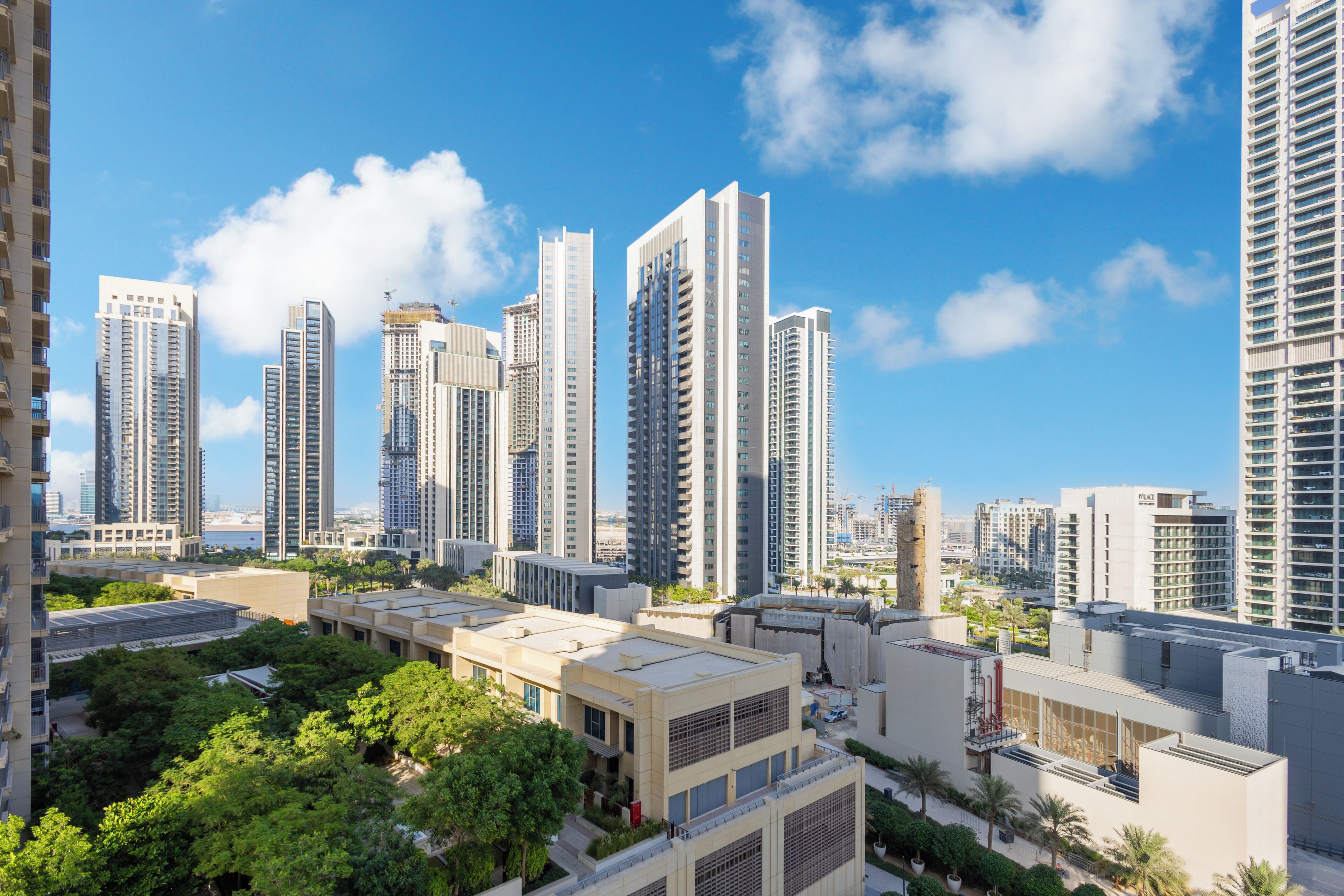 Un immeuble résidentiel de grande hauteur doté de nombreux balcons, d’un jardin sur le toit et offrant une vue dégagée sur le paysage urbain environnant.
