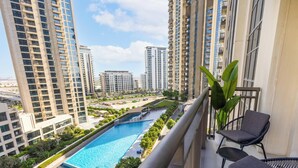 Un balcón con vistas a una piscina, rodeado de edificios altos.