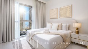 Habitación de hotel con una cama grande, una mesita de noche, una lámpara y dos cuadros en la pared.