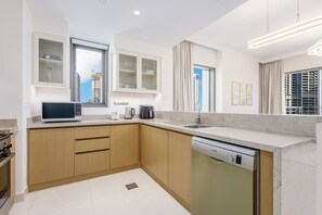 A modern kitchen with a built-in dishwasher, a microwave, and a coffee maker on the countertop. - LUX  The Creekside Skyline View Suite (Dubai)