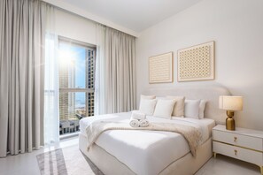 A hotel room with a large bed, a bedside table, a lamp, and two wall art pieces. - LUX  The Creekside Skyline View Suite (Dubai)