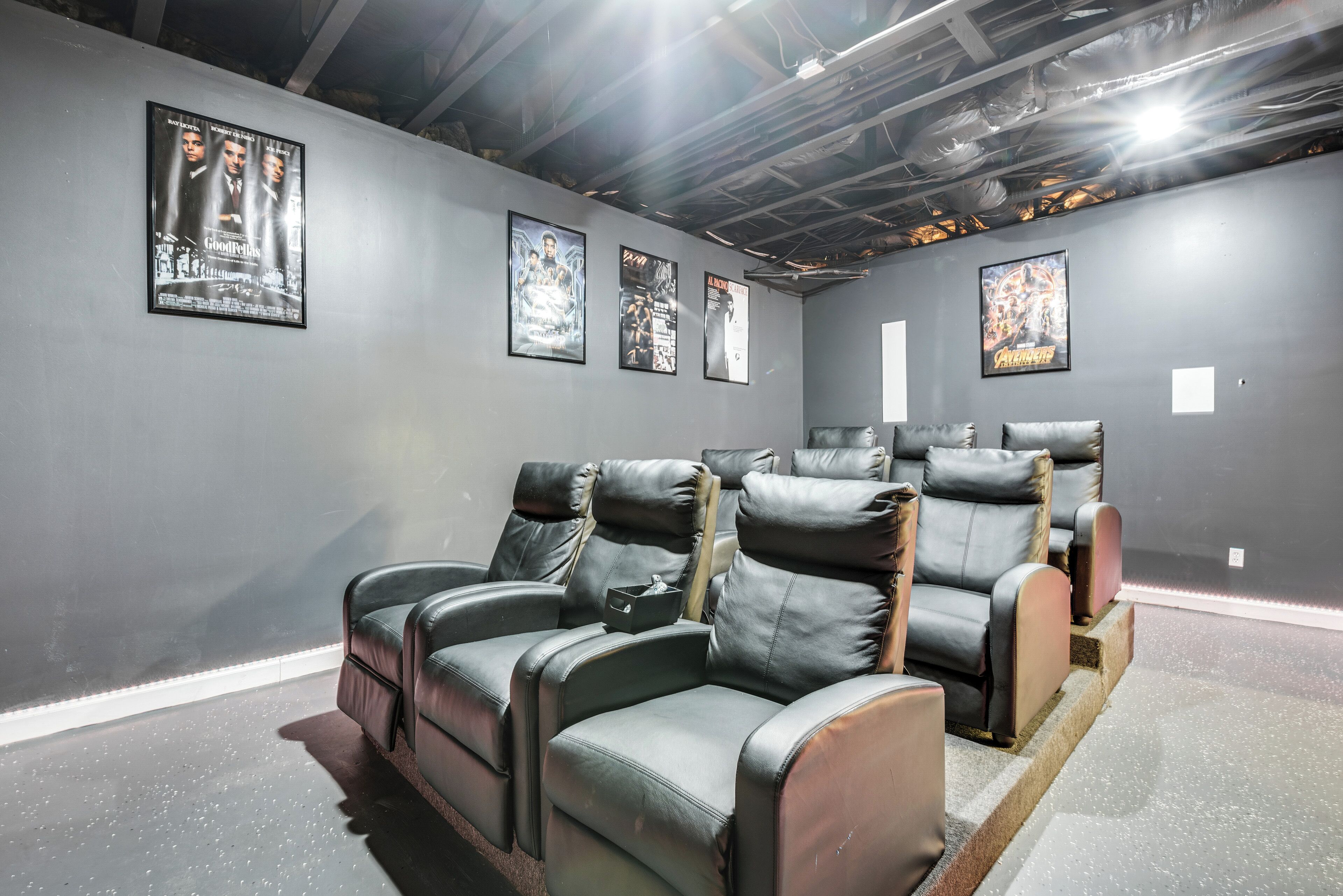 A home theater with leather reclining chairs, a popcorn bucket, and movie posters on the wall.
