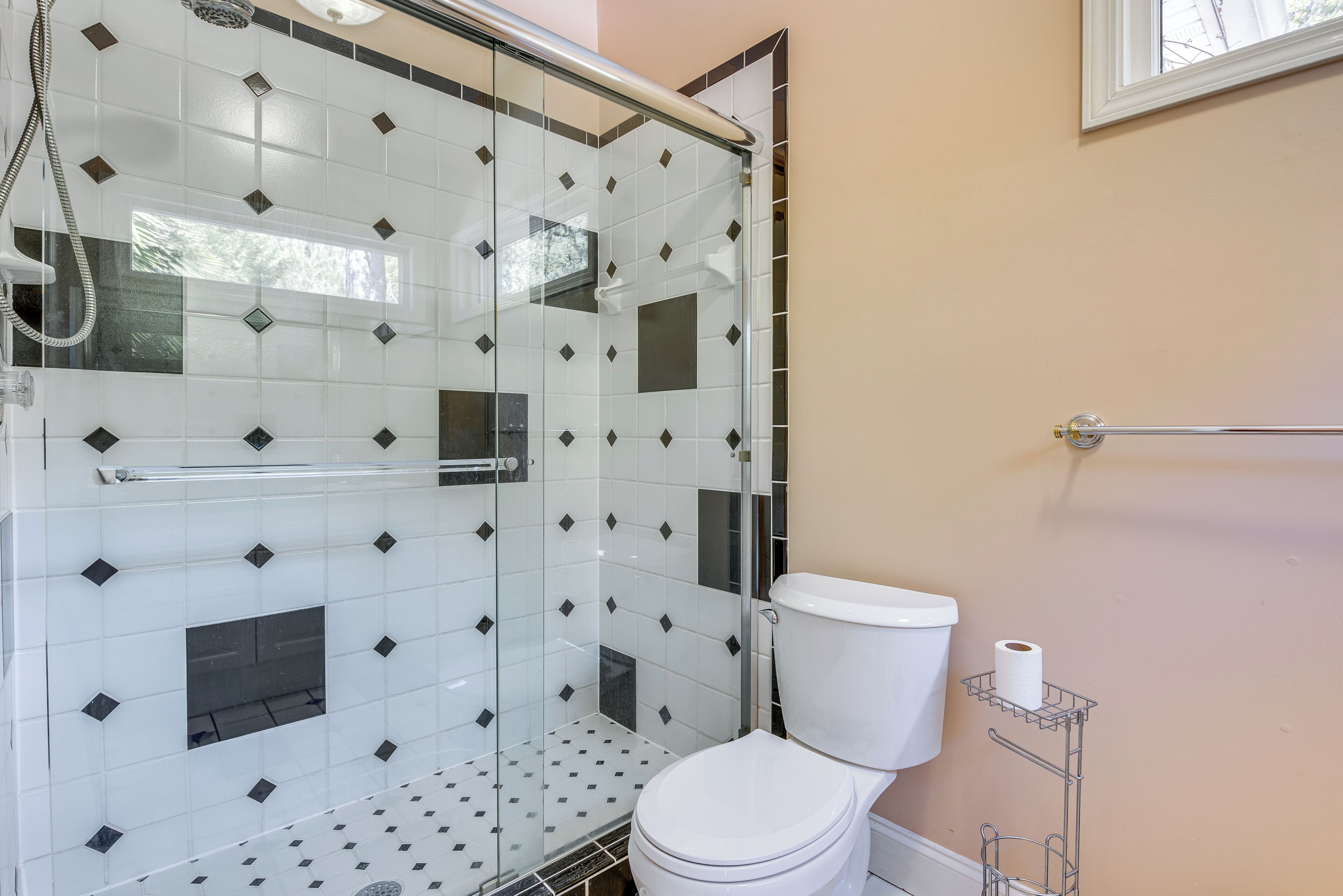 Une salle de bain avec une douche à parois de verre, des toilettes blanches et un porte-serviettes.