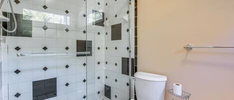 Une salle de bain avec une douche à parois de verre, des toilettes blanches et un porte-serviettes.