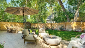 Un patio con mobiliario exterior, una chimenea y un paraguas grande.