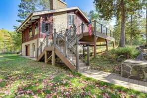 Een lodge met een stenen gevel, een houten terras en een trap naar een balkon met een Amerikaanse vlag.