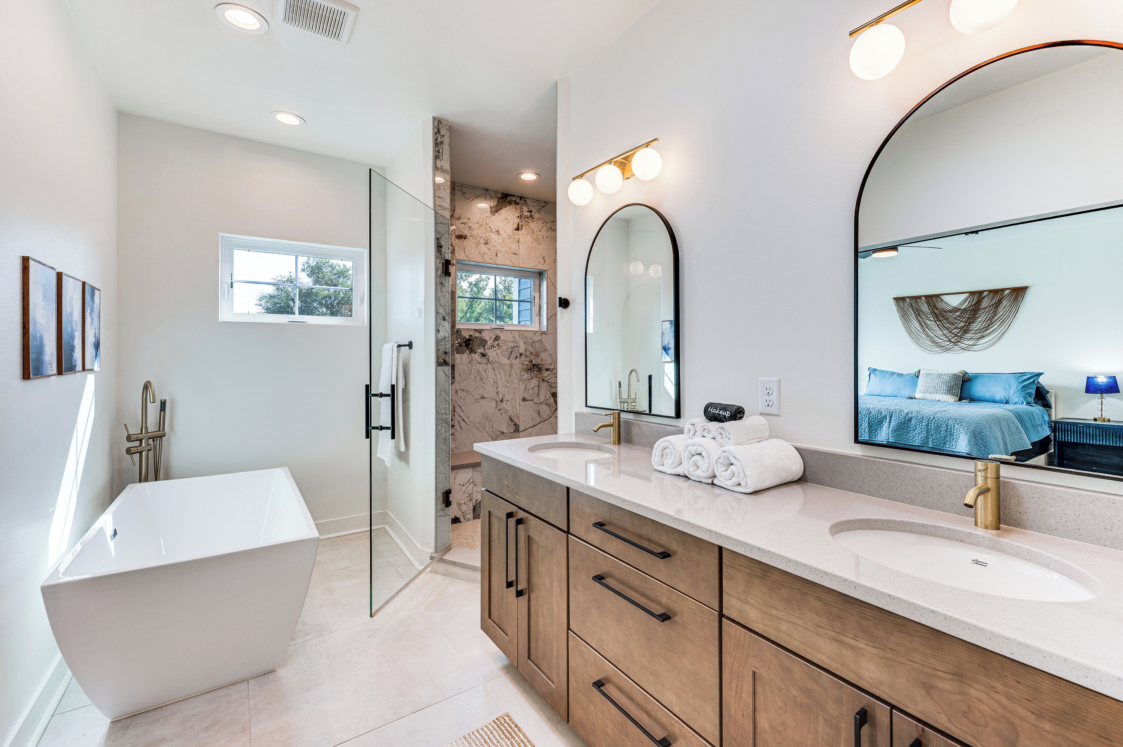 A modern bathroom with a freestanding bathtub, dual sinks, and a large mirror.