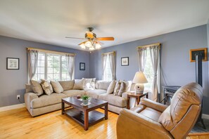 A living room with a beige sofa, a wooden coffee table, a leather armchair, and a ceiling fan.