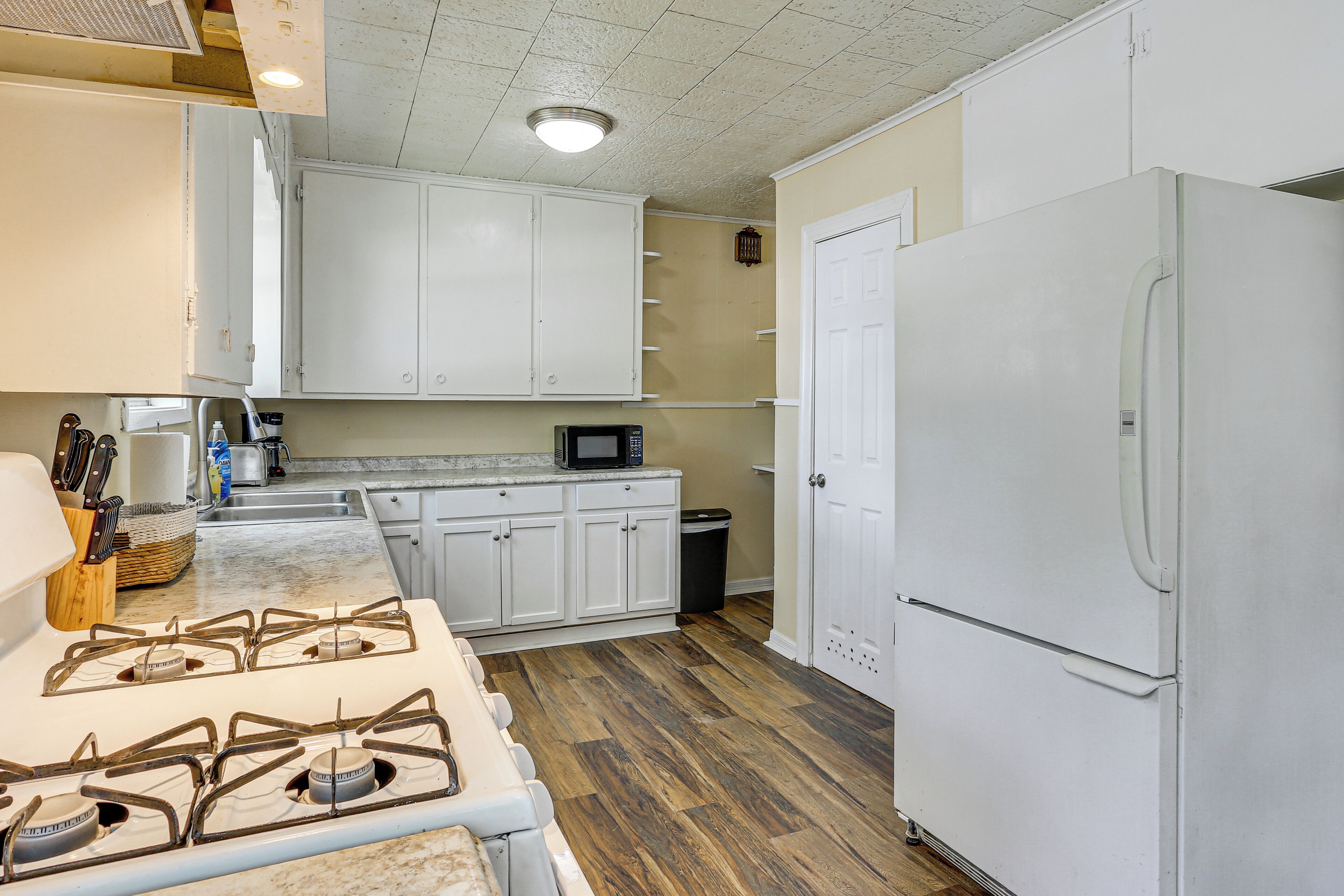 A kitchen with white cabinets, a stove, a microwave, and a refrigerator.