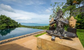 A statue of a seated figure with a backdrop of a pool and a scenic view. - Ban Kinaree (Koh Samui)