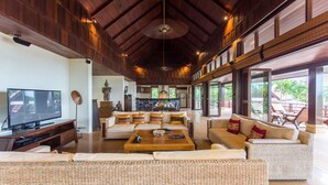 A spacious living area with a large television, comfortable seating, and a view of the outdoors. - Ban Kinaree (Koh Samui)