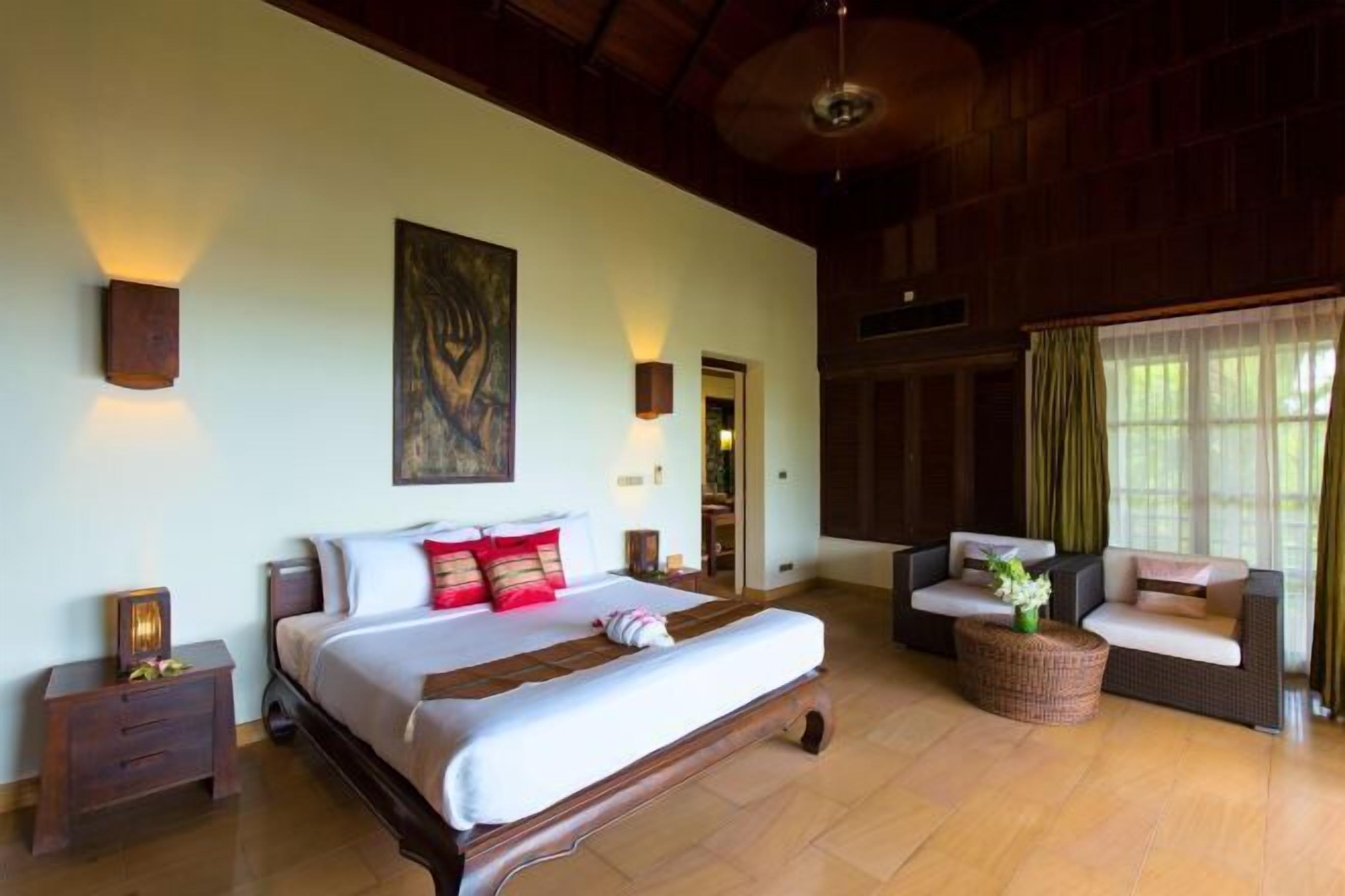 A spacious bedroom with a large bed, a sofa, and a wicker coffee table.