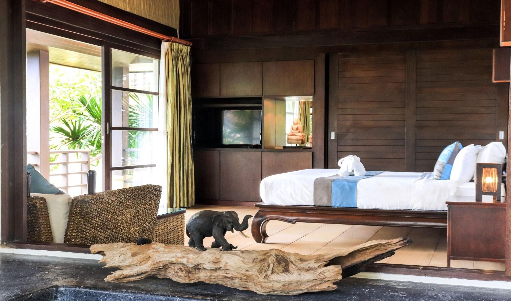 A bedroom with a bed, a television, a statue, and a wooden headboard.