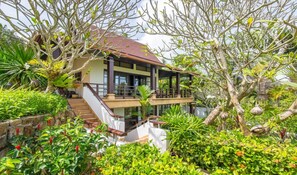 A two-story house with a balcony, surrounded by lush greenery and a stone wall. - Ban Kinaree (Koh Samui)