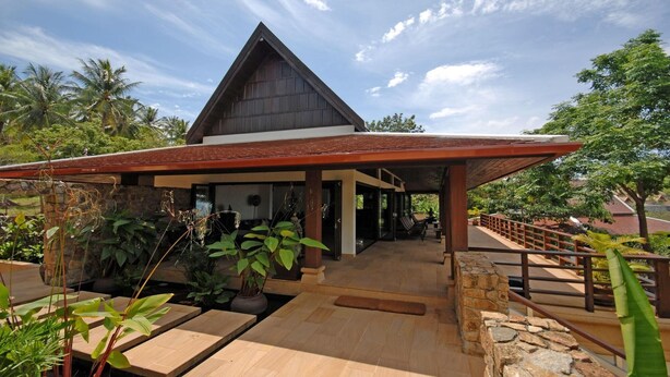 A modern building with a triangular roof, a covered entrance, and a stone pathway leading to the entrance. - Ban Kinaree (Koh Samui)