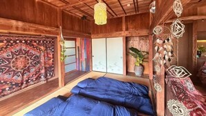Ein Zimmer mit Holzboden, einem Bett, einer Wandteppich und einer Pendelleuchte.