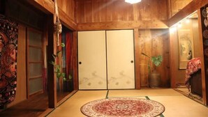 Ein traditioneller japanischer Raum mit Tatami-Böden, Schiebetüren und einer Holzbalkendecke.