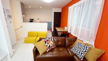 A living room with a brown leather sofa, yellow sofa, and a dining table.