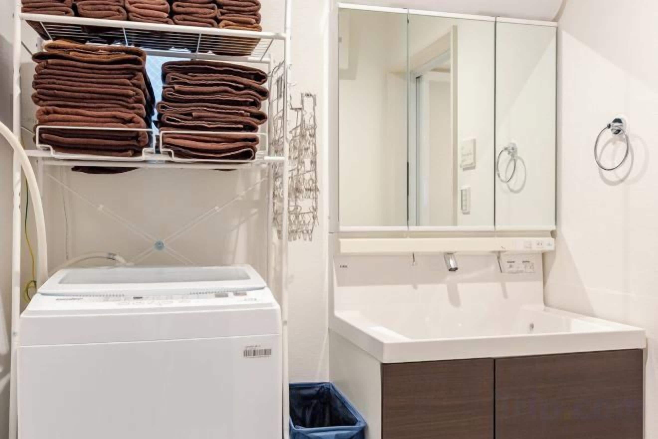A hotel bathroom with a white sink, a mirror, and a towel rack with folded towels.