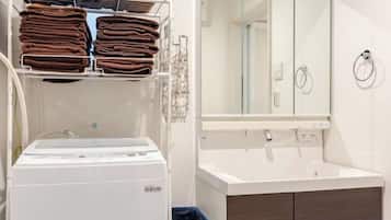 A hotel bathroom with a white sink, a mirror, and a towel rack with folded towels.