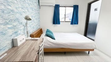 A bedroom with a bed, a desk, a chair, a lamp, and a window with curtains.