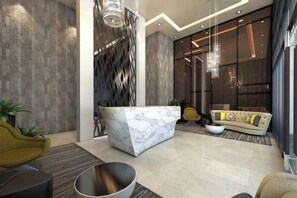 A modern lobby with a marble reception desk, a sofa with cushions, a yellow chair, and a large window. - WS Hotel (Taguig)
