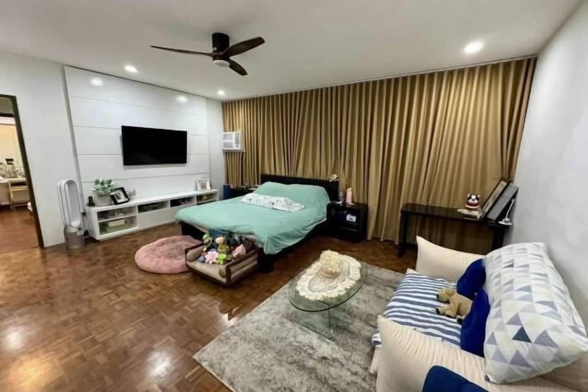 A modern bedroom with a bed, a TV mounted on the wall, a ceiling fan, and a wooden floor.