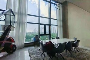 A modern office space with a large table and chairs, a staircase, and a view of the city through large windows. - WS Hotel (Taguig)