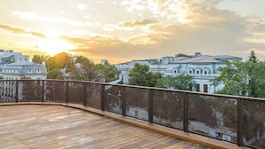 A wooden deck with a metal railing, overlooking a cityscape with historic buildings and trees during sunset. - NISHANI BOUTIQUE MOTEL (Bucharest)