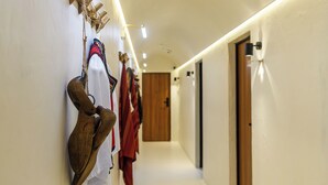 A hallway with a wooden door at the end, a coat rack with various items, and recessed lighting. - NISHANI BOUTIQUE MOTEL (Bucharest)