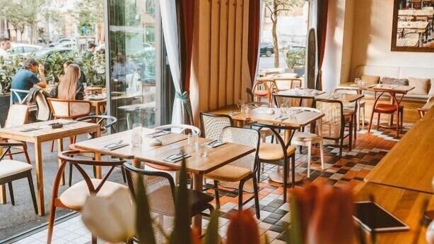 An indoor cafe with tables and chairs, large windows, and a view of the outside. - NISHANI BOUTIQUE MOTEL (Bucharest)