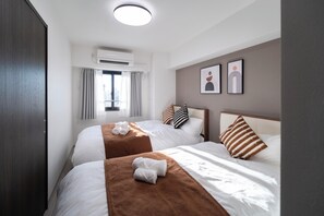 A hotel room with two beds, a window with curtains, an air conditioning unit, and artwork on the wall. - The Peak Kuromon (Osaka)
