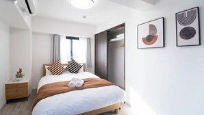 A modern hotel room with a bed, a wardrobe, a nightstand, and two framed artworks on the wall. - The Peak Kuromon (Osaka)