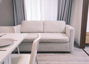 A modern living room with a sofa, a dining table, and a chair. - The Peak Kuromon (Osaka)