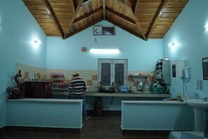 A kitchen with wooden ceiling beams, a window, and a refrigerator.