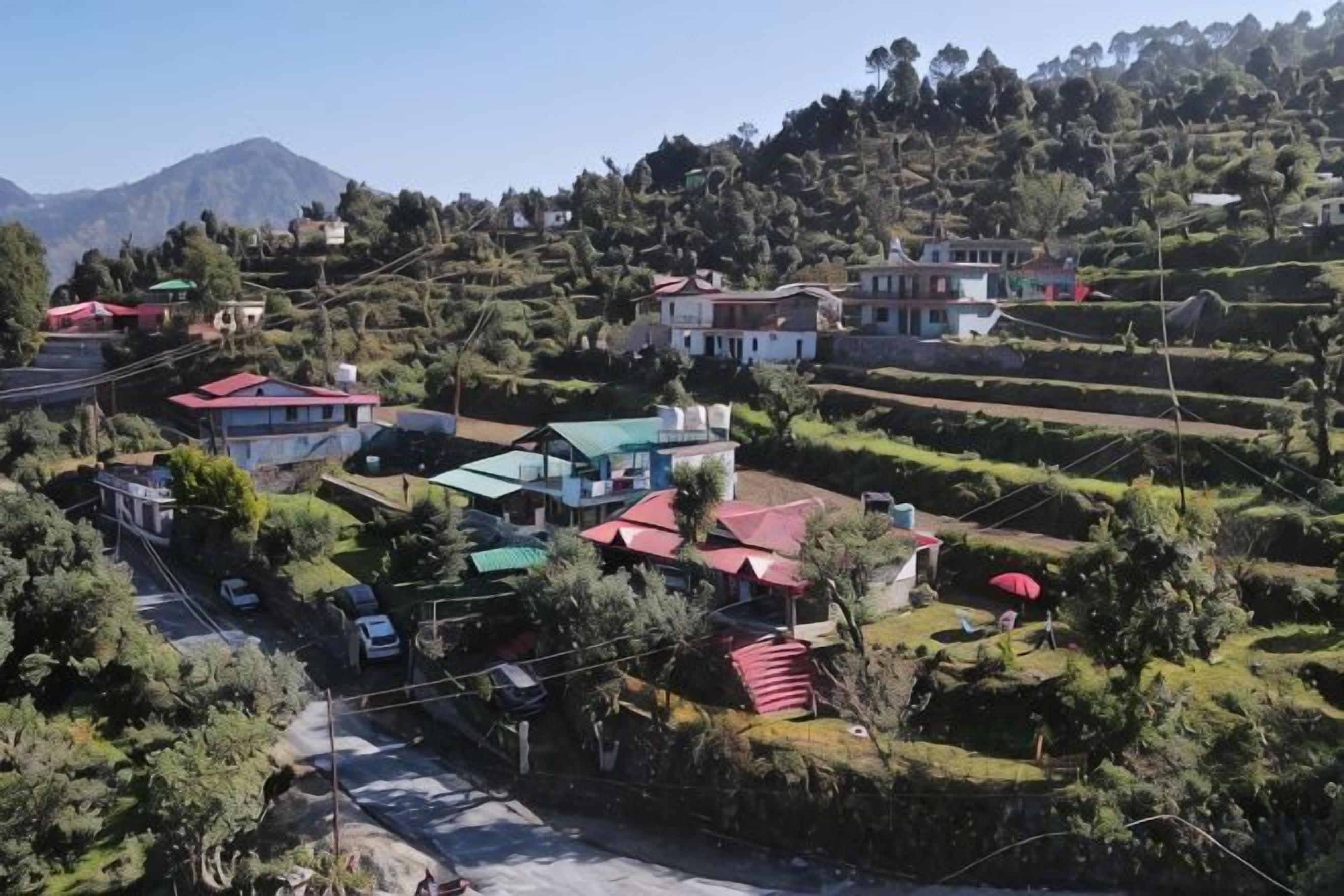 A residential area with houses on terraced hills, a clear sky, and a mountain in the background.