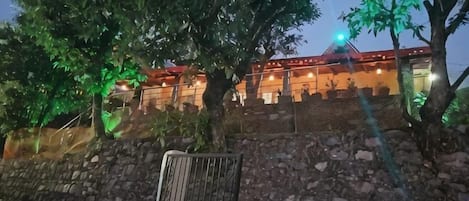 Un edificio con un muro de piedra y una reja de metal, rodeado de árboles.